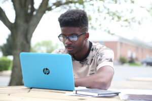 A man working at a laptop on a picnic table. 