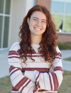 dana smiling in front of academic building