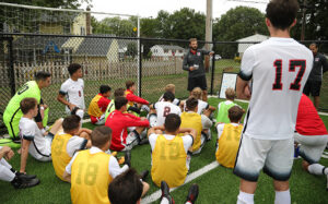 Men's Soccer Head Coach Tommy Ardt, back in black jersey, gives pointers to the Chargers. 