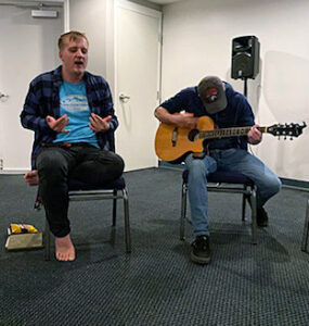 Community Prayer Worship Club founder Kyle Kolynych ('24), left, worships with his fellow students at a recent CPW gathering. 