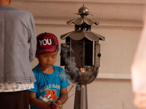 A boy makes a sacrifice at a Buddhist temple.