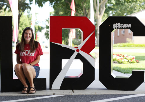 A student sits in large LBC letters